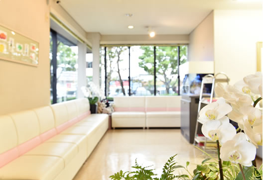 写真：松隈産婦人科クリニック内観　白地にピンクの模様が入ったソファが壁伝いにあり、大きな窓がある
