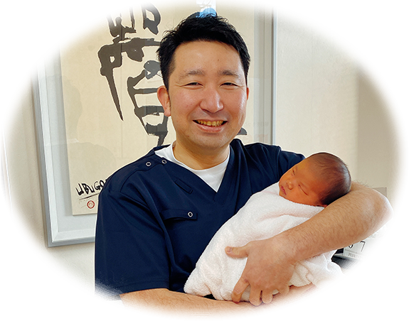画像：赤ちゃんを抱いている笑顔の健先生
